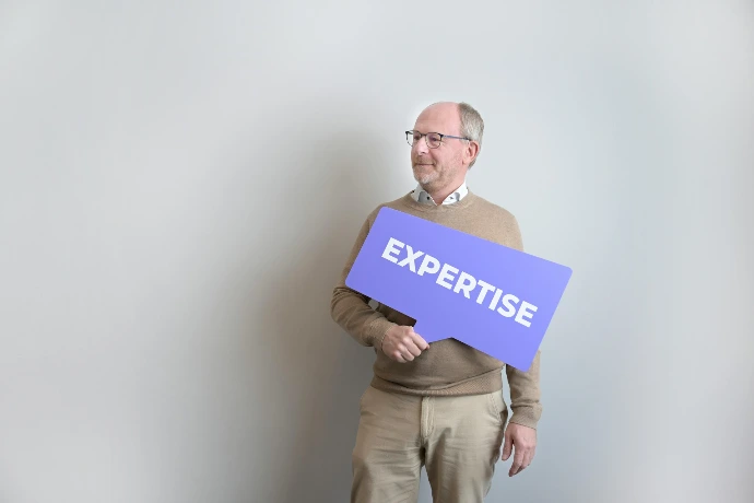 Man holding an "expertise" sign looking left